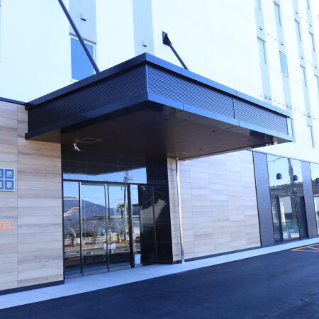 ホテル入り口のアルミ幕板パネル施工例。目地の通りとシャープな水平ラインを追求した納まり　金属工事　アルミパネル