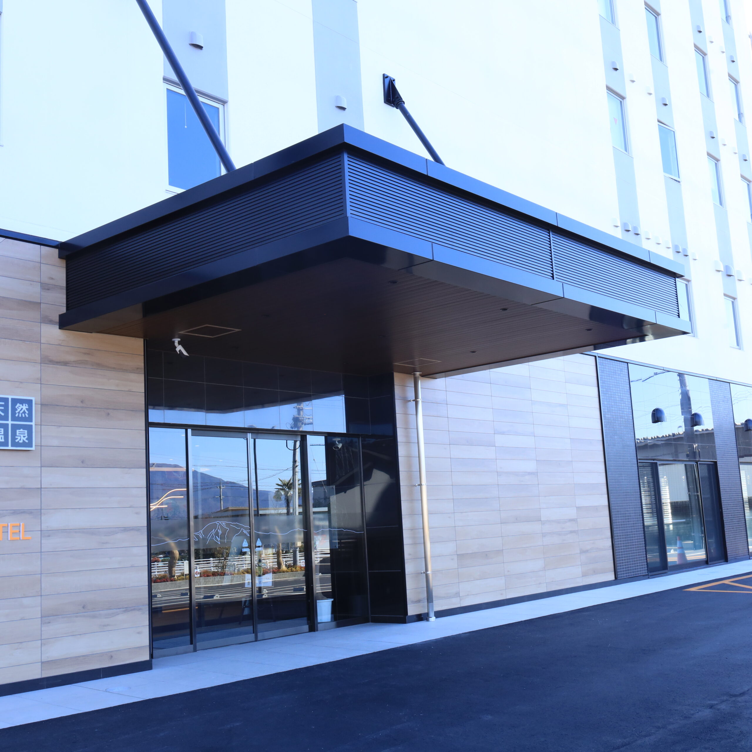 ホテル入り口のアルミ幕板パネル施工例。目地の通りとシャープな水平ラインを追求した納まり　金属工事　アルミパネル