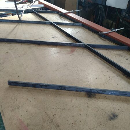 スチール手摺の製作工程。自社での現場実測データを反映した施工図に基づき、塗装前の骨組みを溶接・組み上げている工場作業の様子